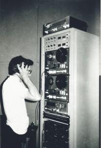 Operador de áudio em processo de gravação, com fitas de rolo.